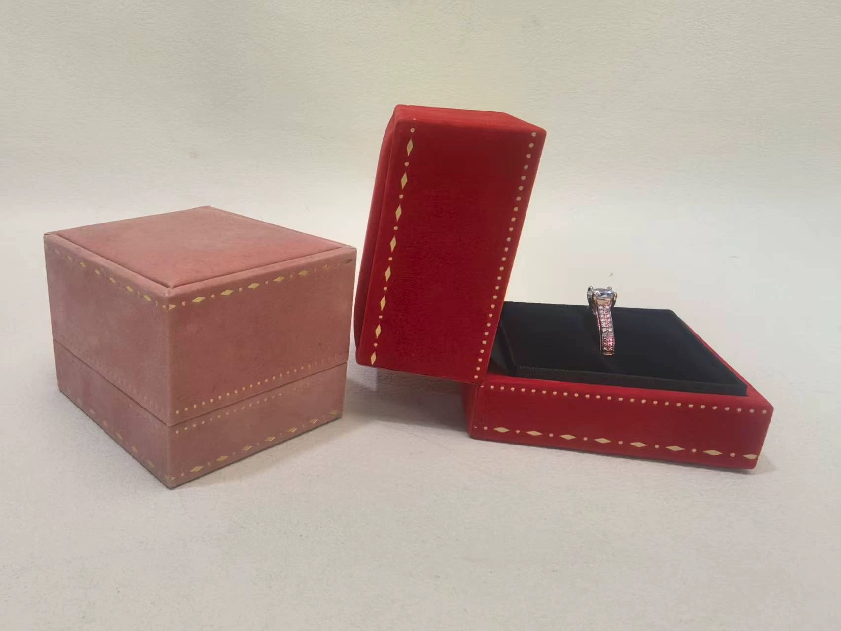 Close-up of the ins lace-edge velvet jewelry box showing the fine gold dotted-diamond trim and soft velvet, a blush-pink box closed beside an open box holding a solitaire ring