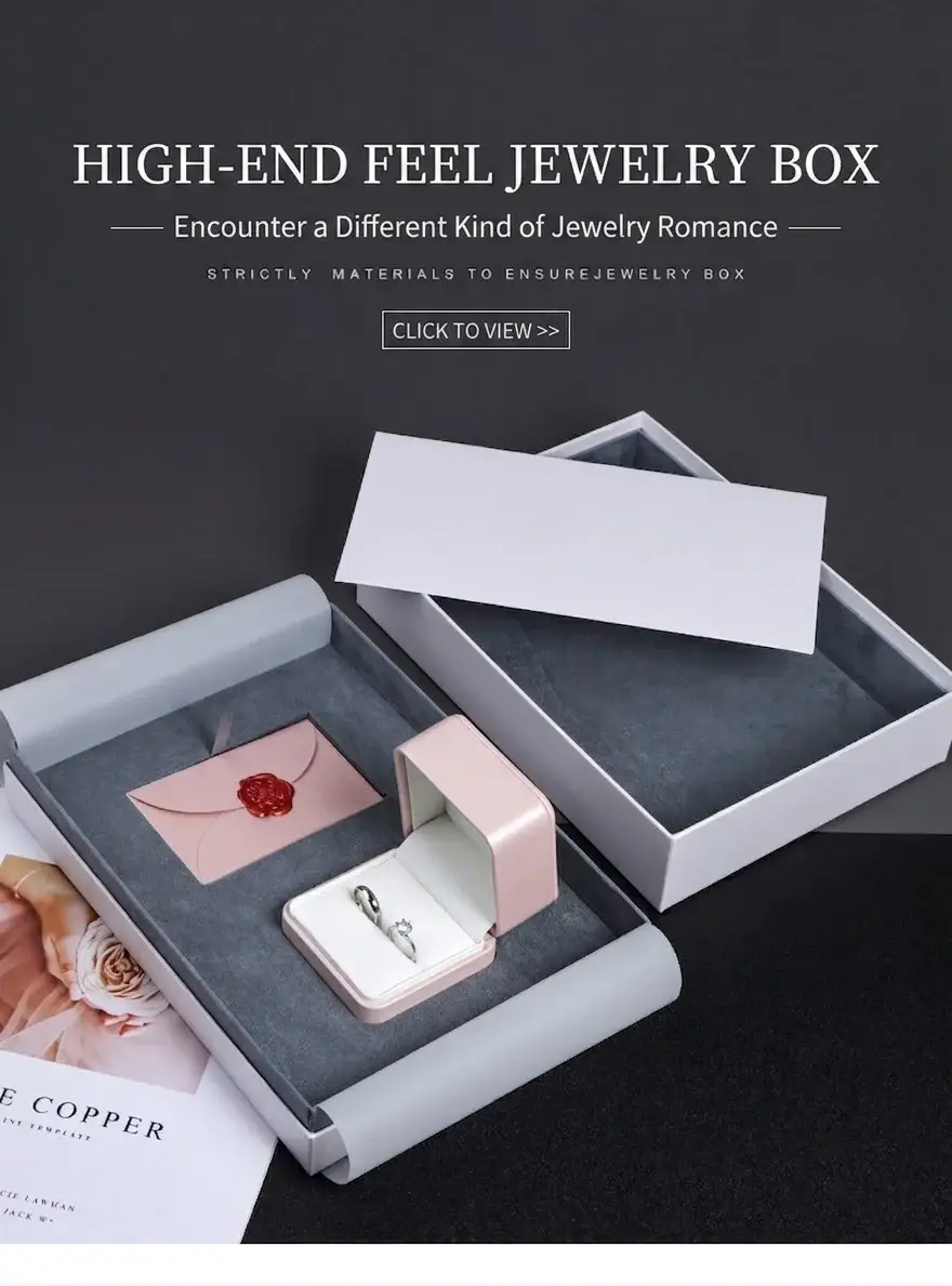 High-end proposal ring gift box set open, showing a blush-pink ring box with twin rings and a wax-sealed envelope on a grey microfiber tray