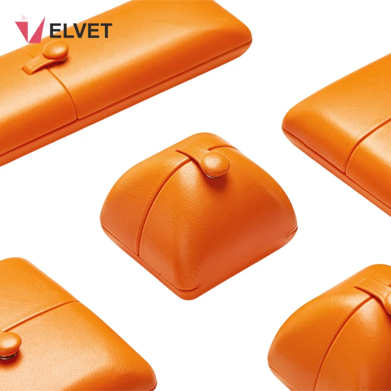 Orange PU leather wedding ceremony ring box set with metal snap-tab lids, showing the domed ring box, the flat square pendant box and the long necklace box closed on a white background