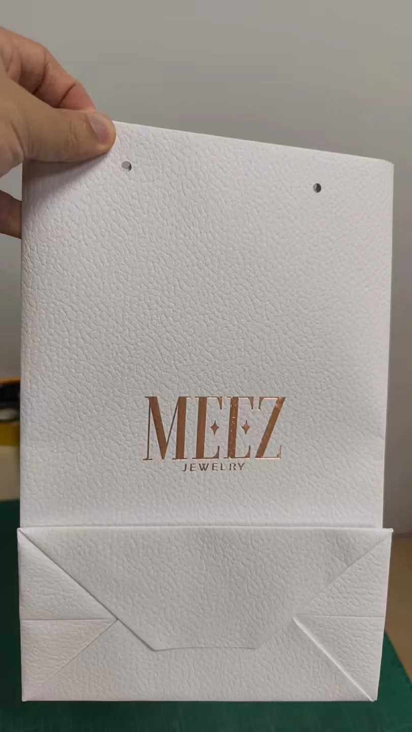 White textured jewelry packaging sample with rose gold foil logo