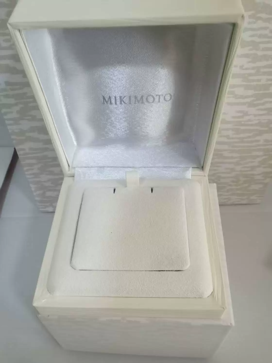 White MIKIMOTO sample jewelry box open from above, showing the flip-top lid and fitted jewelry insert