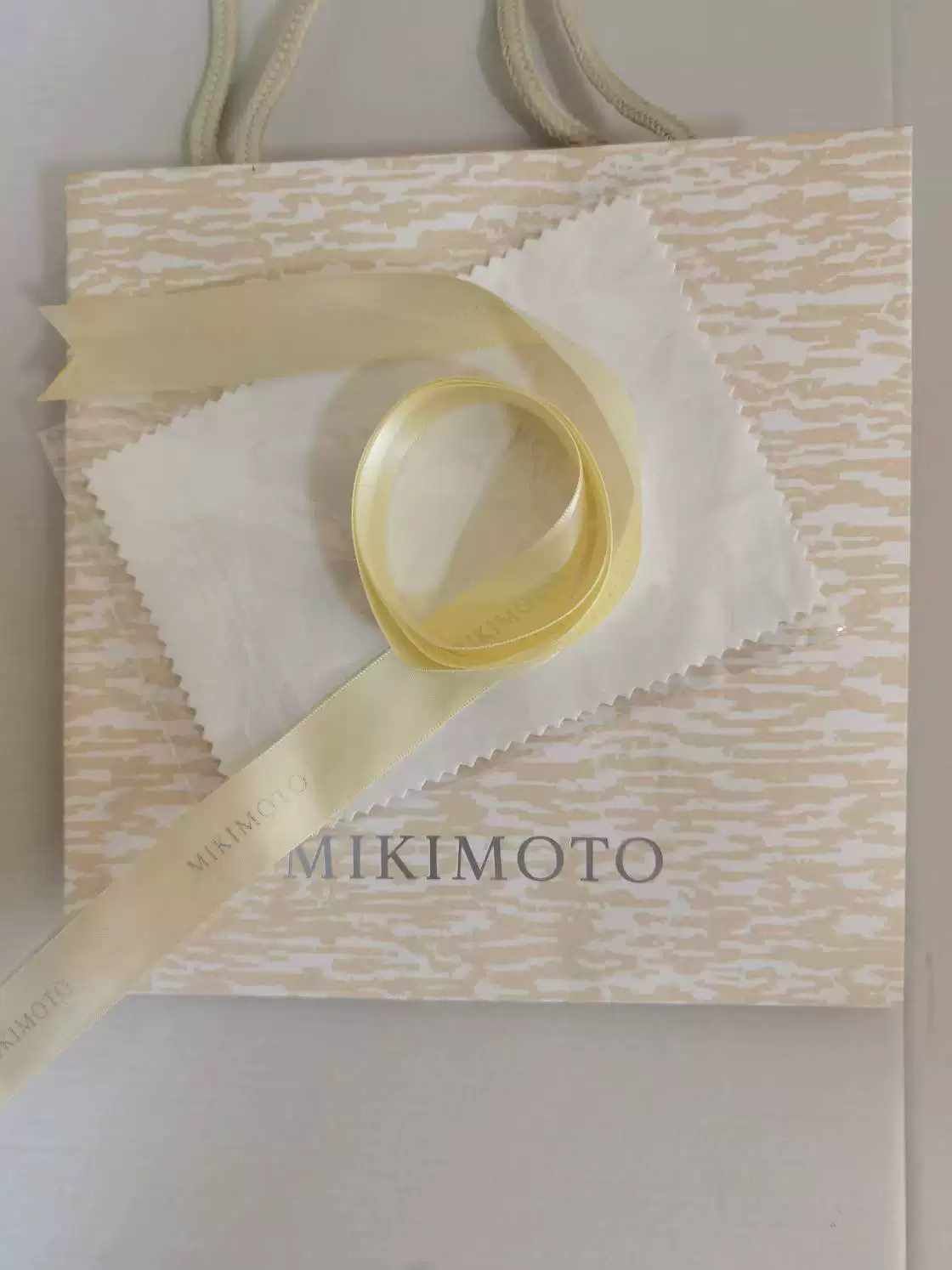 White MIKIMOTO sample jewelry gift packaging with a branded paper bag and ribbon